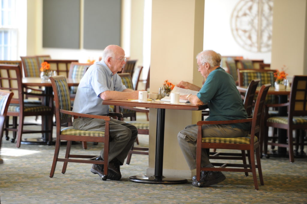 Two male residents talking at table in a dining room