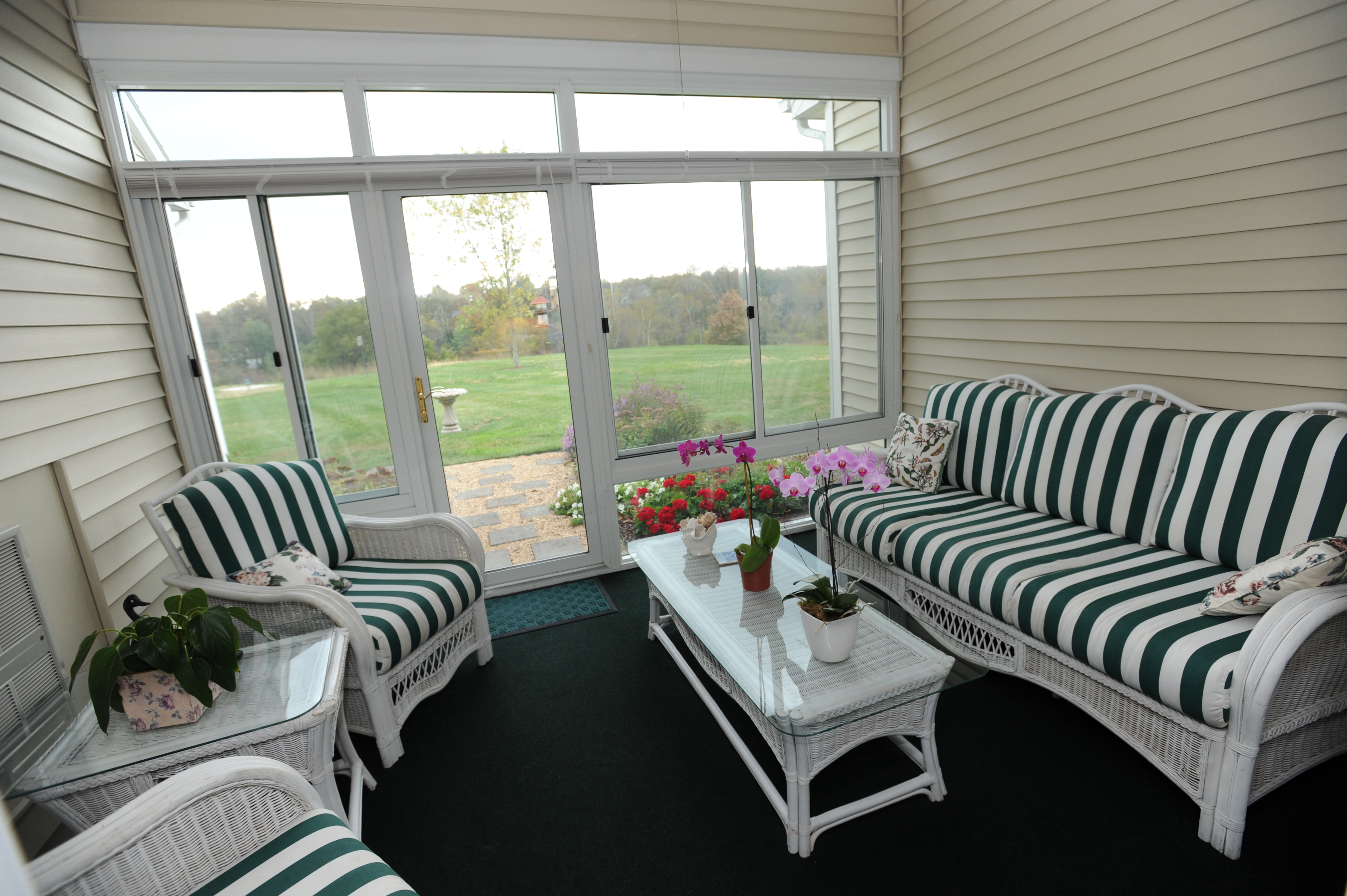 Screened porch with white rattan furnishings