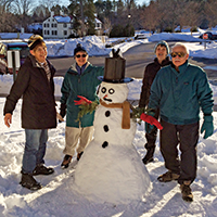 Four residents standing around a snowman they just built