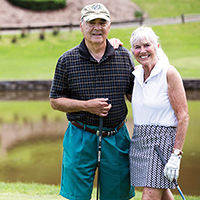 resident couple George and Melou holding clubs at a golf course