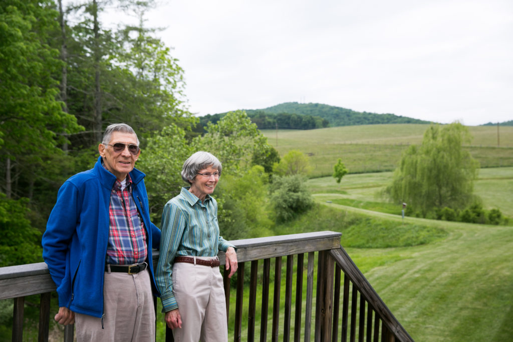 Resident couple on their deck overlooking rolling green hills and a Blue Ridge Mountain peak