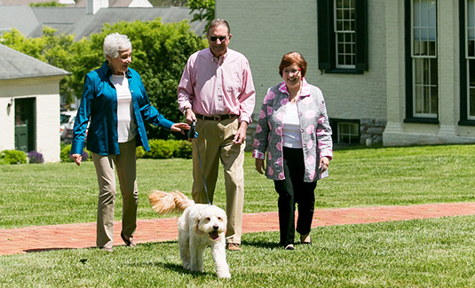 Resident couple walking a white dog along with a friend