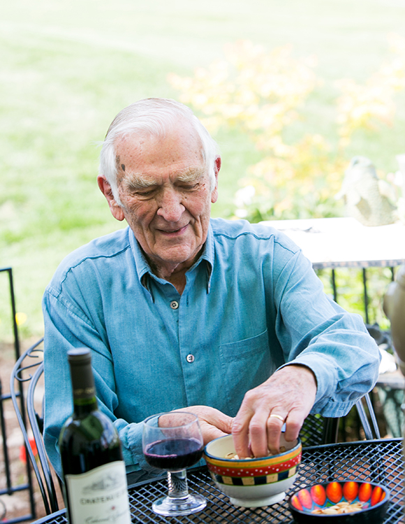 Male resident on patio with a glass and bottle of wine enjoying a snack