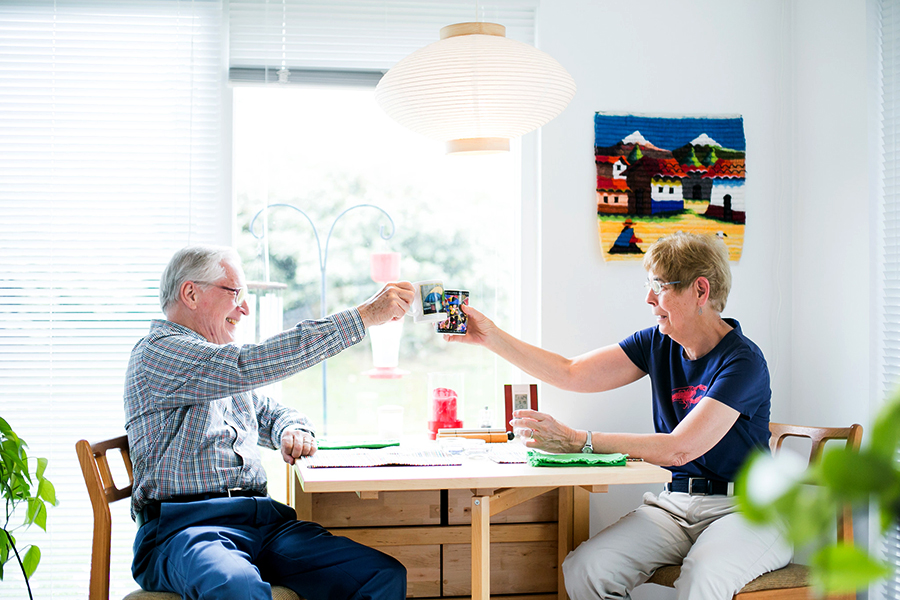 Couple toasting each other with coffee mugs at kitchen table