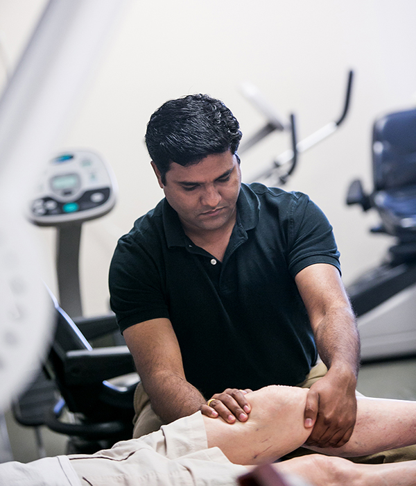 Physical therapist working on the knee of a resident who is lying down