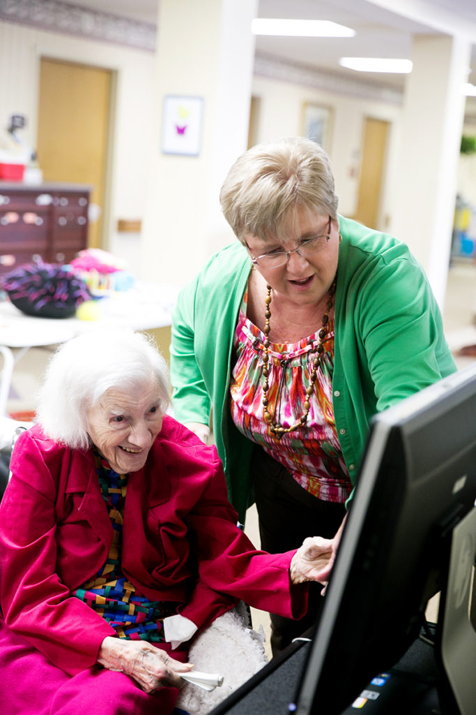 Staff member helping a resident who is using a computer
