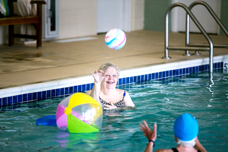 Female residents playing with beach balls in the indoor pool
