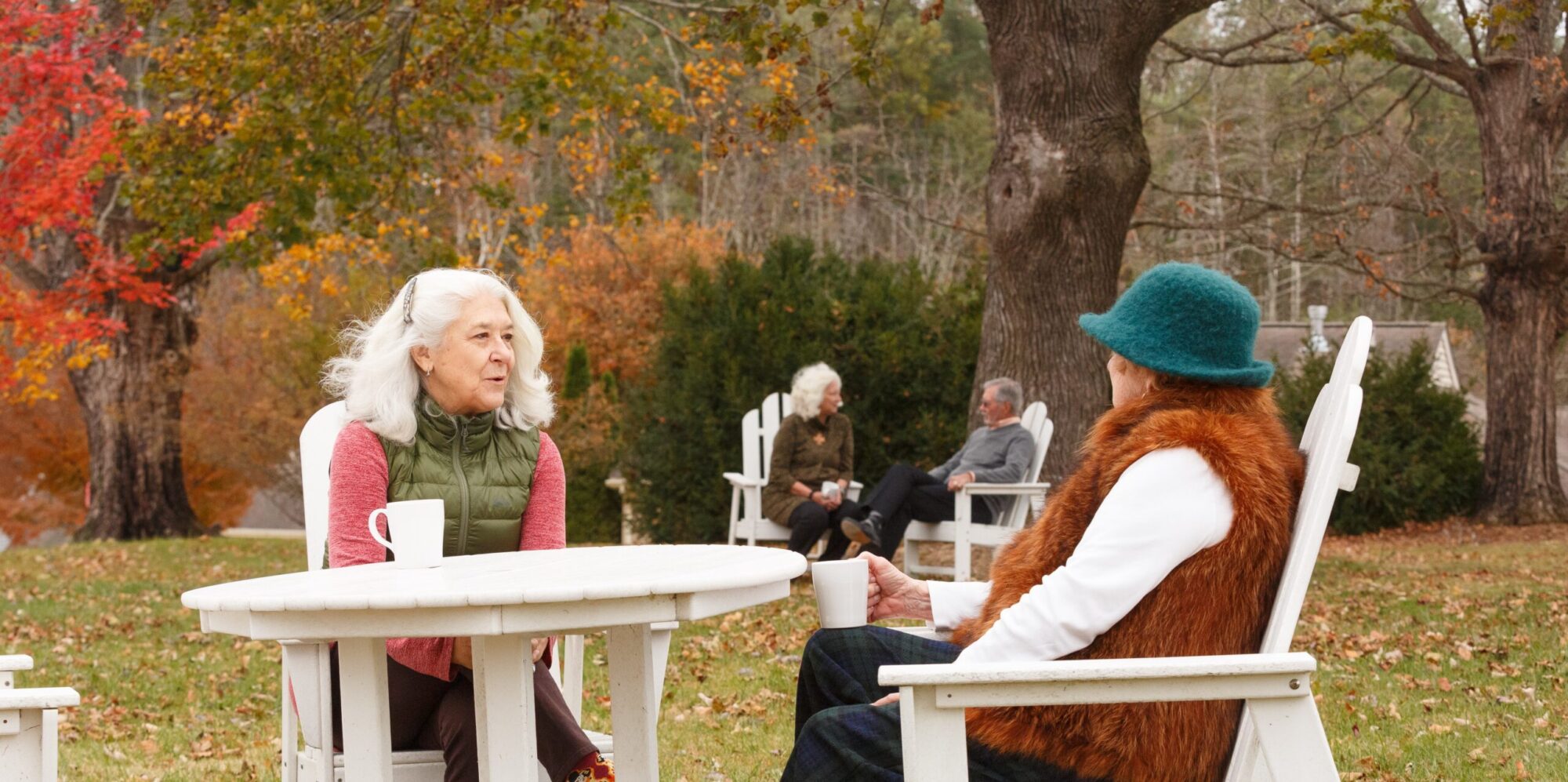 Residents enjoying coffee at an outside table on a Fall day.